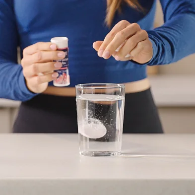 MaxiNutrition Hydration Tabs – Frau bereitet Elektrolyt-Drink im Glas zu