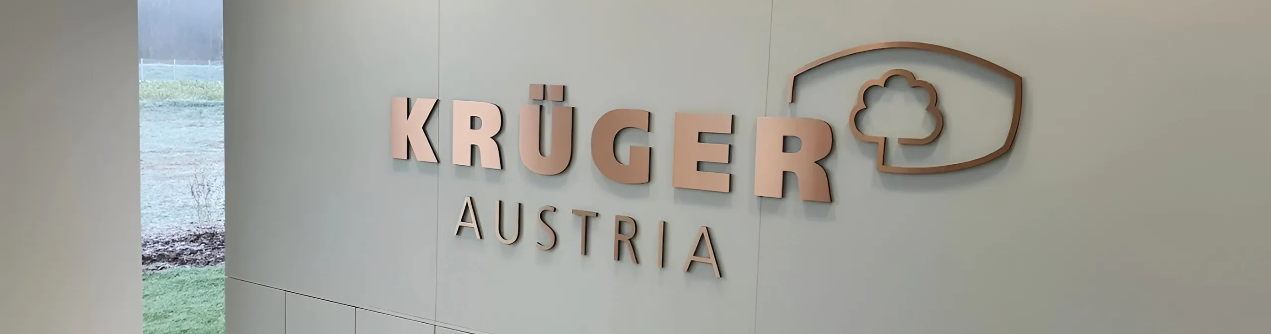 Krüger Austria Logo als Metallschriftzug an der Empfangswand im Eingangsbereich